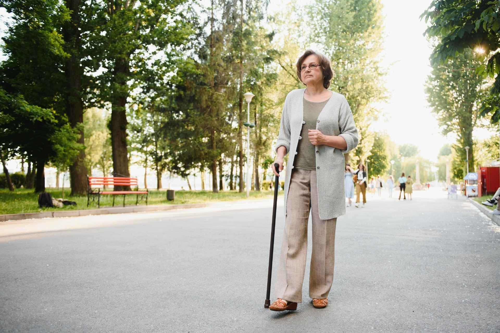 A senior woman is taking a walk with a cane.